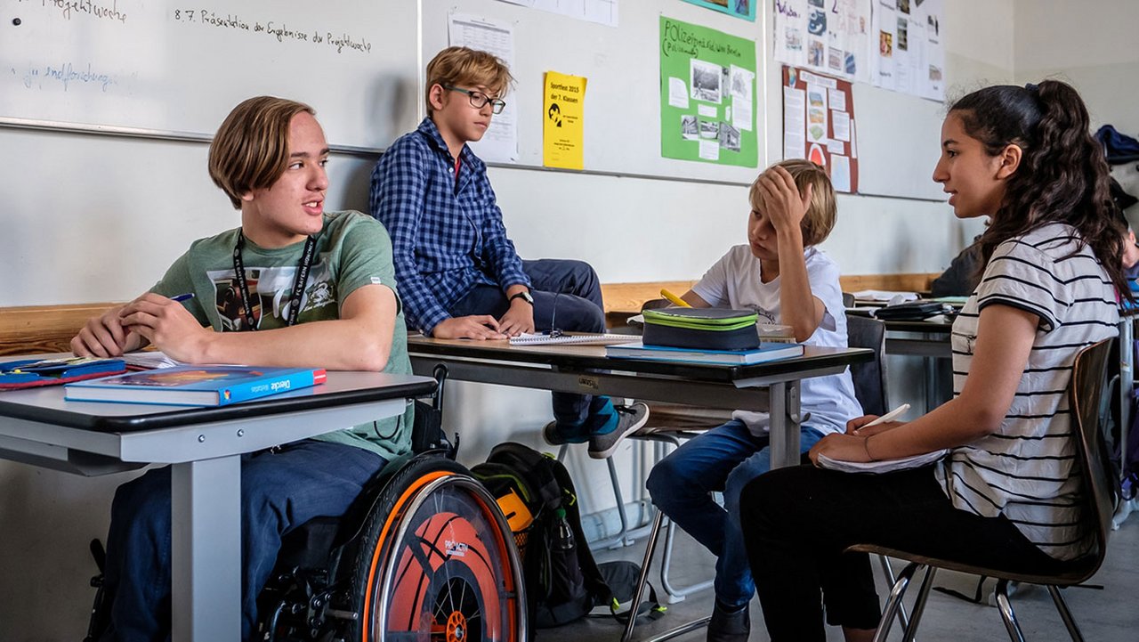 Vier Schüler sitzen beisammen in einem Klassenzimmer.