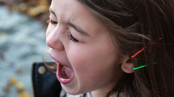 Nahaufnahme der Gesichtszüge eines Kindes mit braunen Haaren. Es hat die Augen geschlossen und den Mund zu einem Schrei geöffnet.